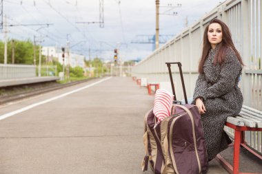 Bir boş tren istasyonu bir çanta ile kız. Tren bekliyor