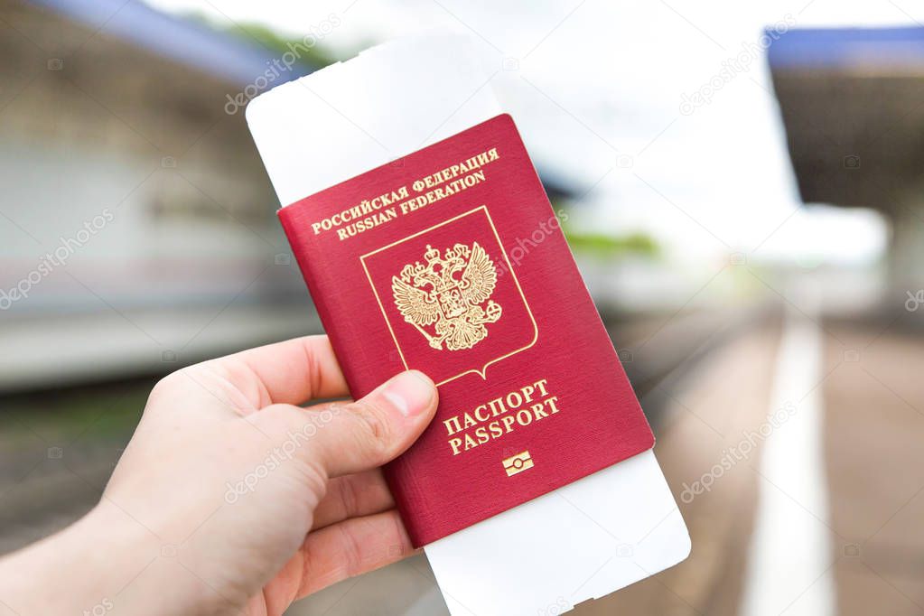 Hand with a passport and tickets on a light background