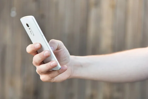 Un hombre toma fotos en un teléfono inteligente. Primer plano de la mano y el gadget en posición vertical — Foto de Stock