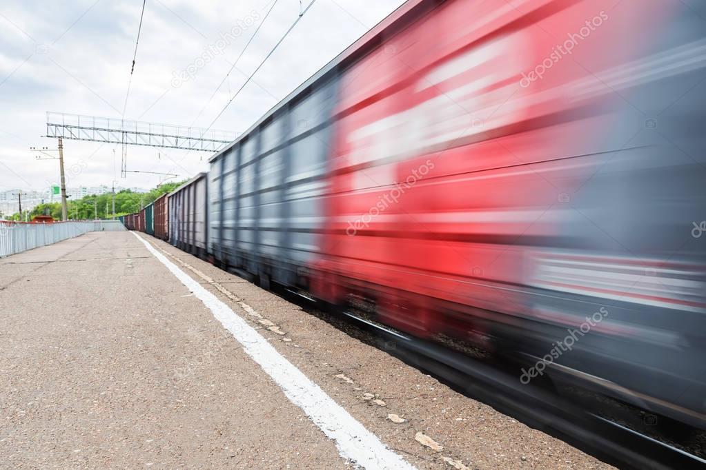 The freight train in motion is passing by the station. Russian Railways
