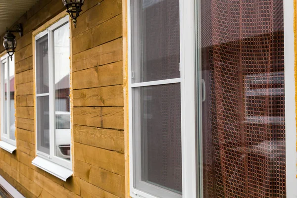 Пластиковые окна на фасаде загородного дома из дерева — стоковое фото