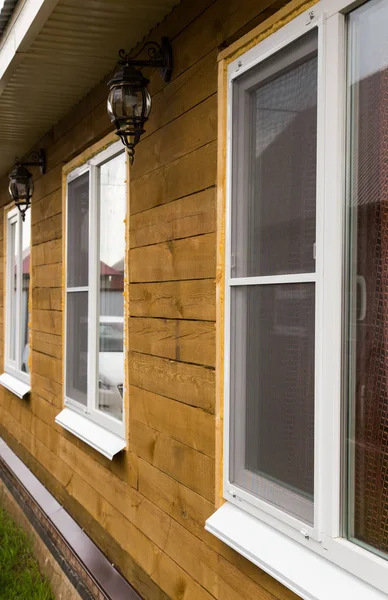 Пластиковые окна на фасаде загородного дома из дерева — стоковое фото