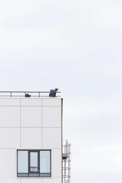 UFA, RÚSSIA - 21 de maio de 2016: Idel Tower. Engenheiro em um capacete fica na borda do telhado de um edifício moderno — Fotografia de Stock