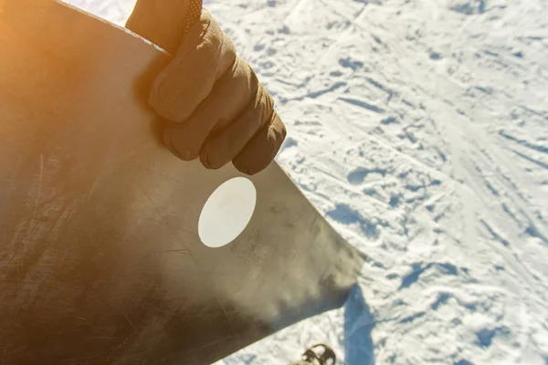 Birinci şahıs bakış. el bir snowboard günbatımı arka plan üzerinde tutar. — Stok fotoğraf