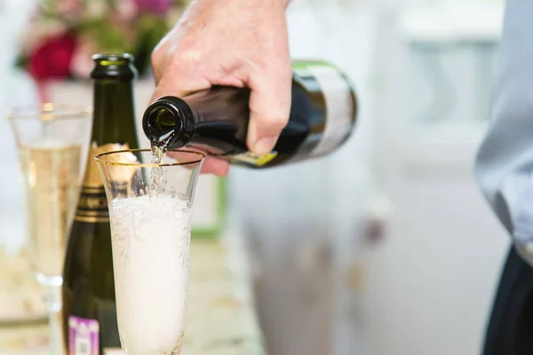 La mano de un hombre vierte champán de una botella en una copa — Foto de Stock