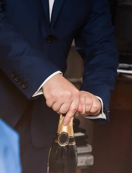 La mano de un hombre vierte champán de una botella en una copa — Foto de Stock