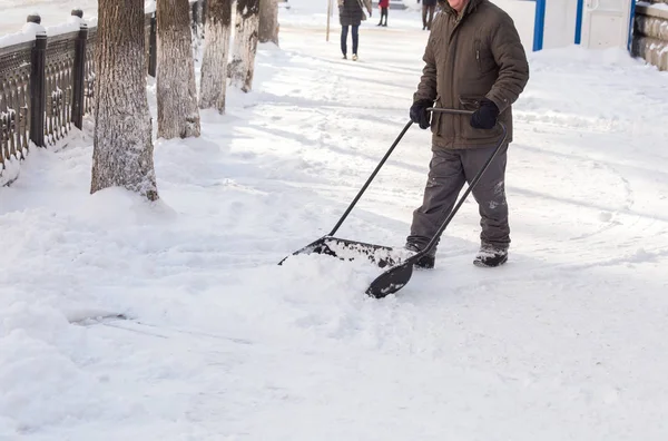 Man met schop reinigt de sneeuw — Stockfoto