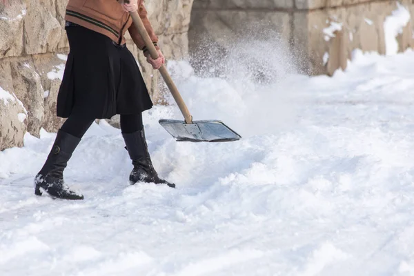 Frau mit Schaufel reinigt den Schnee — Stockfoto