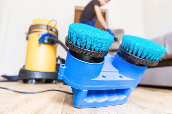 Serviço de limpeza. Homem zelador em luvas e sofá limpo vácuo uniforme com equipamento profissional. Máquina de limpeza rotativa . — Fotografia de Stock