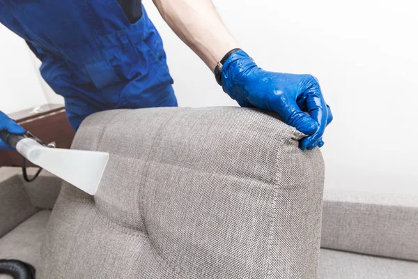 Servicio de limpieza. Conserje de hombre en guantes y sofá de limpieza al vacío uniforme con equipo profesional —  Fotos de Stock