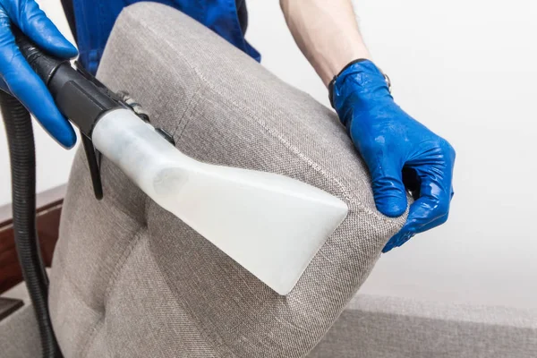 Städning. Man vaktmästare i handskar och enhetlig dammsugare ren soffa med professionell utrustning — Stockfoto