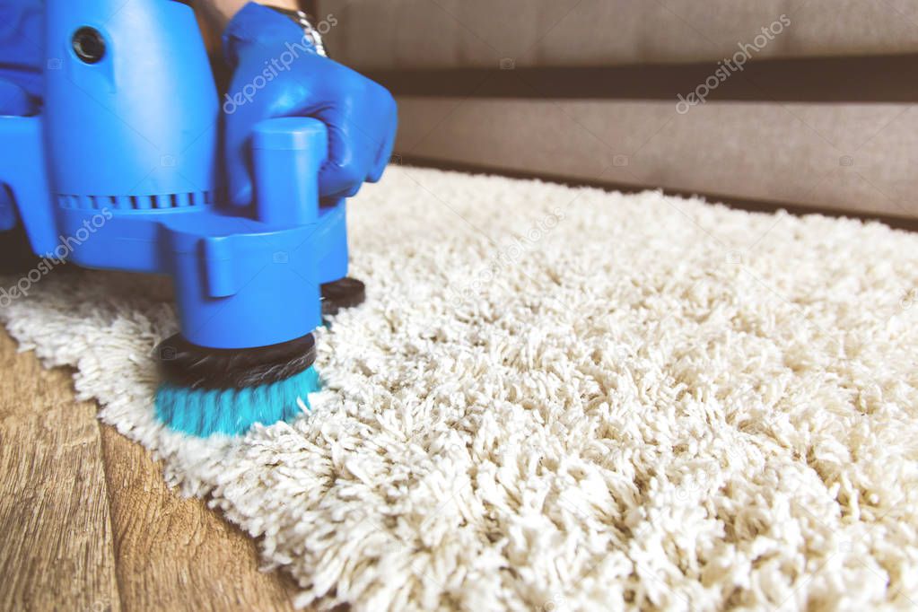 Cleaning service. Man janitor in gloves and uniform vacuum clean white carpet with professional equipment