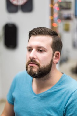 Sakallı bir saç kesimi berber salonu bir koltukta oturuyor sonra genç bir beyaz adam