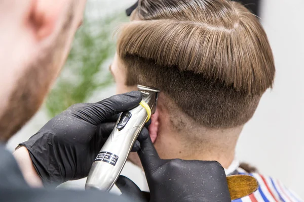 Men\'s haircut in barbershop. Master barber does a haircut to the client. Work with scissors and clipper. Close-up of the workflow
