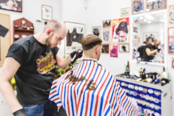 Blurred image of men\'s haircut in barbershop. Master barber does a haircut to the client. Work with scissors and clipper. Close-up of the workflow