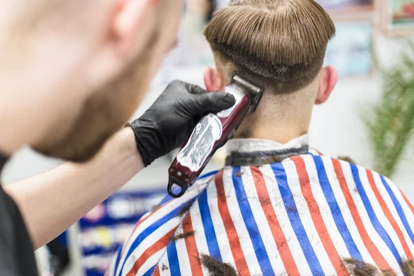 Men\'s haircut in barbershop. Master barber does a haircut to the client. Work with scissors and clipper. Close-up of the workflow