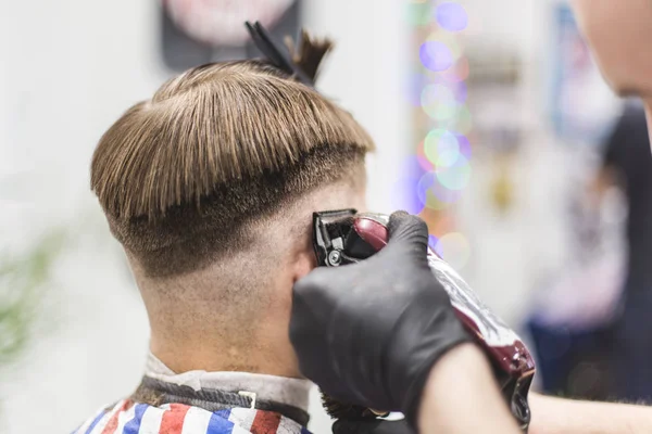 Men\'s haircut in barbershop. Master barber does a haircut to the client. Work with scissors and clipper. Close-up of the workflow