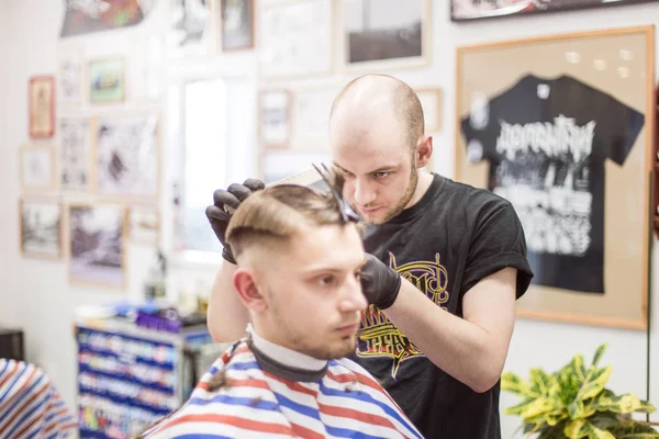 Men\'s haircut in barbershop. Master barber does a haircut to the client. Work with scissors and clipper. Close-up of the workflow