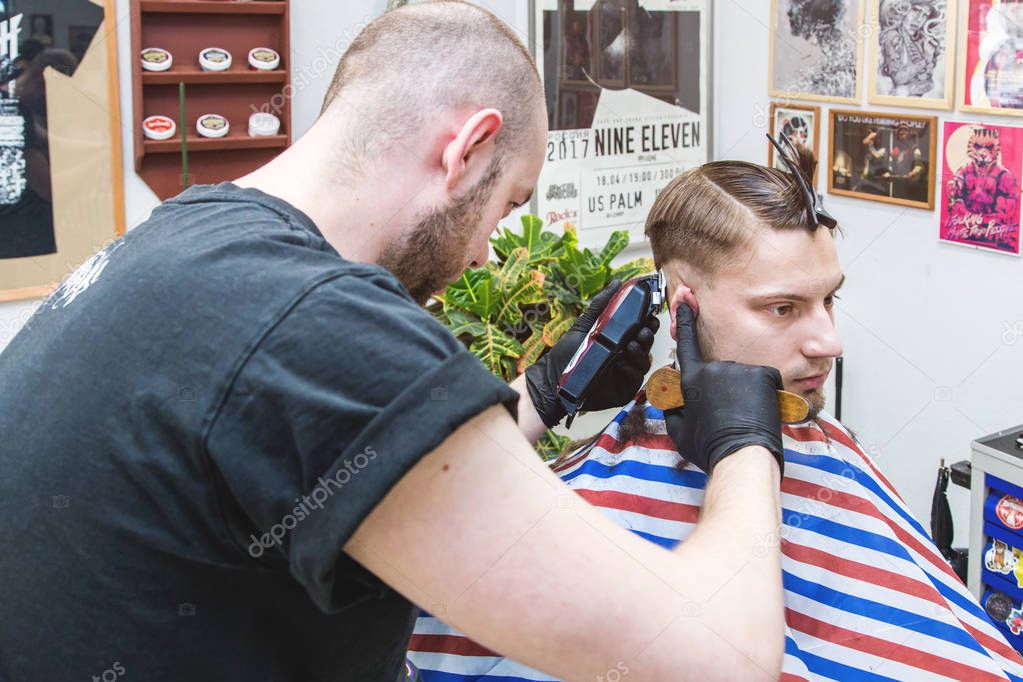 Ufa, Russia. 16 April 2018: Men's haircut in barbershop. Master barber does a haircut to the client. Work with scissors and clipper. Close-up of the workflow