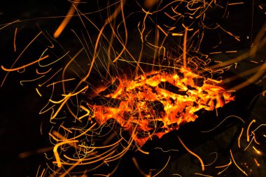 parlak turuncu bir kamp ateşi uzun pozlama ve için için yanan kömürlerin üzerinde gelen kıvılcım. Dynamics satırları izlemeler.