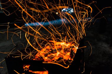 parlak turuncu bir kamp ateşi uzun pozlama ve için için yanan kömürlerin üzerinde gelen kıvılcım. Dynamics satırları izlemeler.