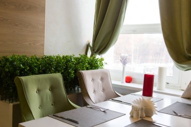 Pencere kenarındaki restoranda samimi bir tablo. Dinlenme ve saat. İç kurumlar