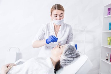 Bir kadın makyajcısı Doktor Genç bir kızın hasta ile çalışır ve bir krem yüzünde uygular. Güzellik ve Cilt Bakımı.