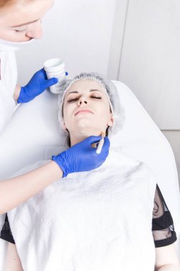 Bir kadın makyajcısı Doktor Genç bir kızın hasta ile çalışır ve bir krem yüzünde uygular. Güzellik ve Cilt Bakımı.