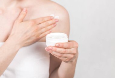 Kız beyaz bir havlu duşta kremi bir kavanoz tutar sonra bir