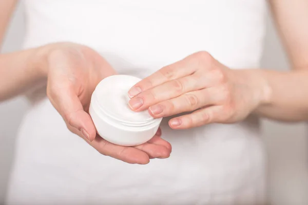 The girl after a shower in a white towel keeps a jar of cream an — Stock Photo, Image