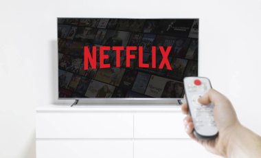 Ufa, Rusya - Jule 7, 2019: Akıllı telefonda patlamış mısır şişesi ve Netflix logosu olan masa. Netflix film ve Tv dizisi akışı küresel bir sağlayıcısıdır
