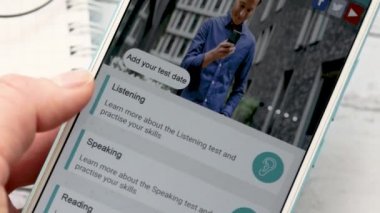Ufa, Russia - March 4: woman holds a smartphone in her ears and passes an English proficiency test IELTS