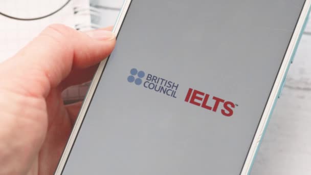 Ufa, Russia - March 4: woman holds a smartphone in her ears and passes an English proficiency test IELTS — Stok video