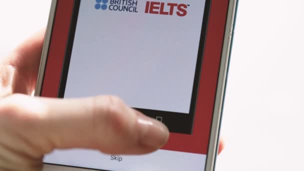 Ufa, Russia - March 4: woman holds a smartphone in her ears and passes an English proficiency test IELTS — Stok video