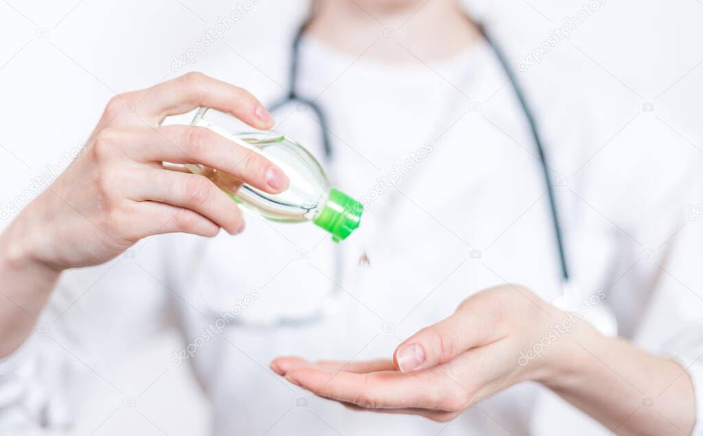 Coronavirus COVI 19 . Young smiling woman brunette doctor in glasses and medical white coat with stethoscope squeezing out a vial with clear liquid in palm