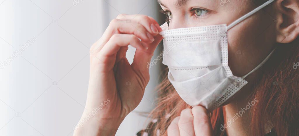 Woman puts on a surgical medical mask. Healthcare concept. New type coronavirus 2019-nCoV