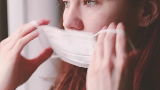 Vrouw zet een chirurgisch medisch masker op. Gezondheidszorg concept. Nieuw type coronavirus 2019-nCoV — Stockvideo