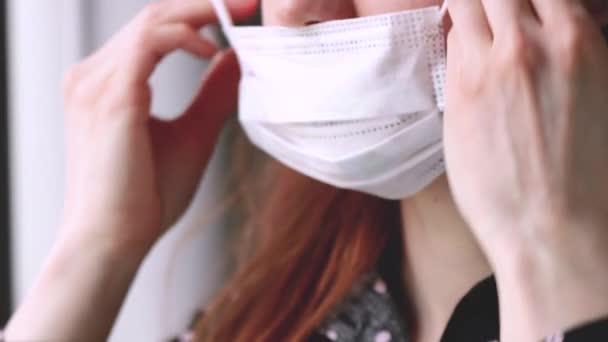 Vrouw zet een chirurgisch medisch masker op. Gezondheidszorg concept. Nieuw type coronavirus 2019-nCoV — Stockvideo