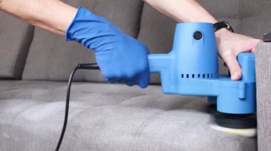 Temizlik servisi. Eldivenli ve elektrikli süpürgeli adam. Profesyonel ekipmanlı temiz kanepe.