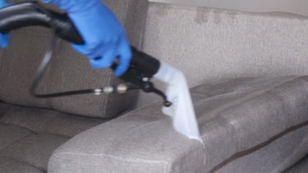Reinigungsservice. Mann Hausmeister in Handschuhen und Uniform staubsaugen Sofa mit professioneller Ausrüstung — Stockvideo