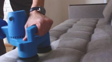 Temizlik servisi. Eldivenli ve elektrikli süpürgeli adam. Profesyonel ekipmanlı temiz kanepe.