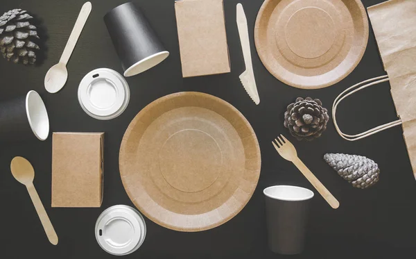 Eco amigável pratos descartáveis feitos de papel sobre fundo preto. Colheres embrulhadas, garfo, facas, prato com copos de papel. conceito de reciclagem — Fotografia de Stock