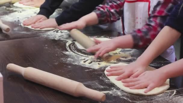 Children cook pizza. Master class from the chef in a restaurant, Close-up of childrens hands roll out the dough — 图库视频影像