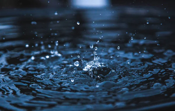 Water splash in donkerblauwe kleur met een druppel water vliegen van boven — Stockfoto