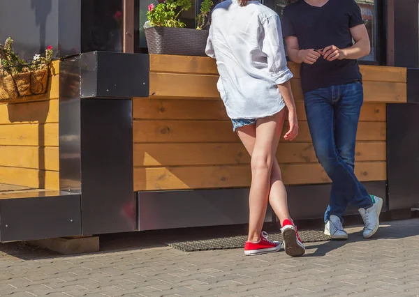 Um jovem e uma menina estão falando na rua esperando por uma ordem na boutique . Imagem De Stock