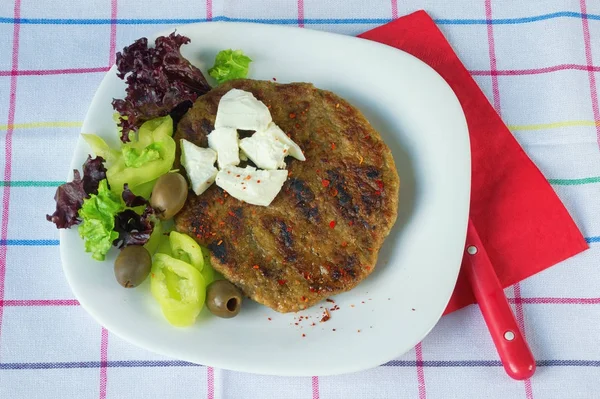 Cozinha balcânica. Pljeskavica - um prato grelhado de carne picada - com queijo e legumes — Fotografia de Stock