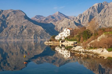 Dağ ve sahil beyaz bina ile suda yansıtılır. Karadağ, Kotor Koyu'nun, Dobrota kasaba
