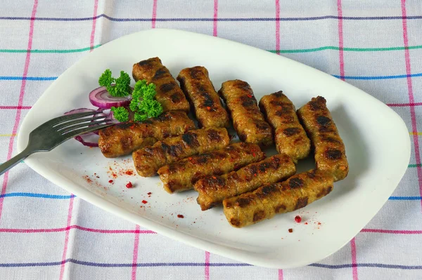 Балканская кухня. Cevapi - жареное блюдо из фарша - на белой тарелке — стоковое фото