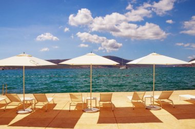 Yaz tatili. Plajda şemsiye ve şezlong güneş. Karadağ, Kotor Koyu'nun Tivat şehir 