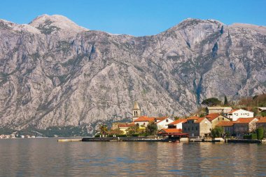 Gri Dağlar karşı kırmızı çatılar ile taş evleri ile küçük bir Akdeniz köy. Karadağ, Kotor Körfezi 